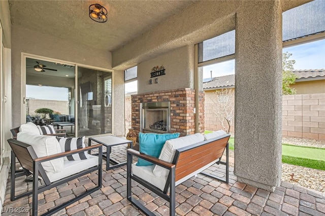 view of patio / terrace featuring an outdoor living space with a fireplace and fence