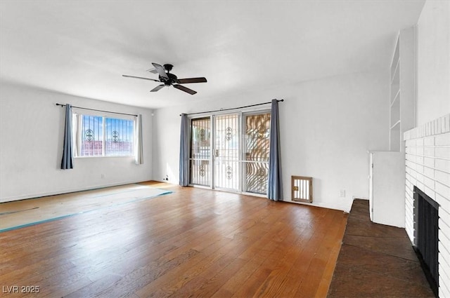 unfurnished living room with a brick fireplace, a ceiling fan, and hardwood / wood-style flooring