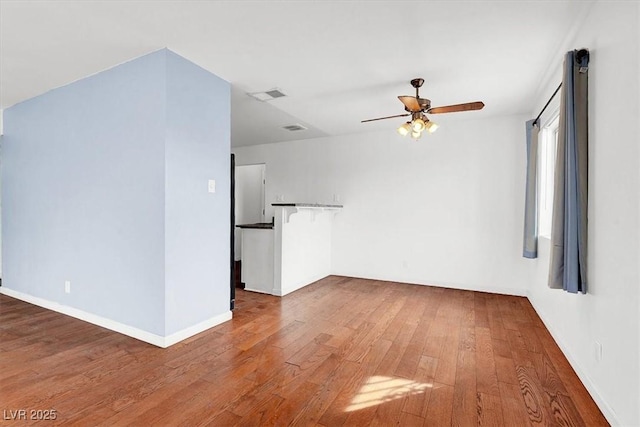 unfurnished room with visible vents, baseboards, hardwood / wood-style floors, and a ceiling fan