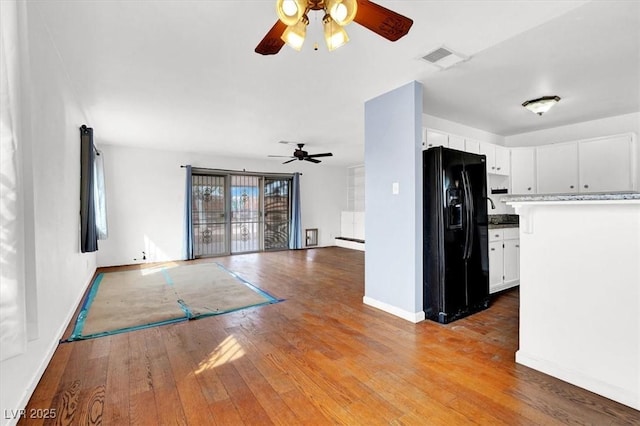 kitchen with visible vents, black fridge, hardwood / wood-style floors, white cabinetry, and ceiling fan