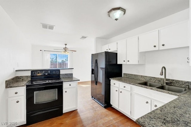 kitchen featuring dark stone countertops, a ceiling fan, a sink, black appliances, and white cabinetry