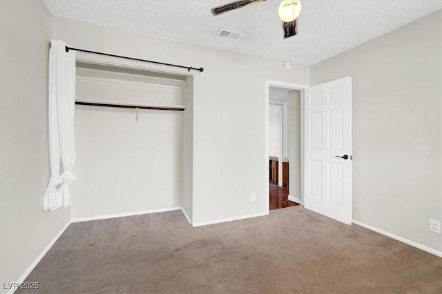 unfurnished bedroom with visible vents, a textured ceiling, a closet, carpet floors, and baseboards