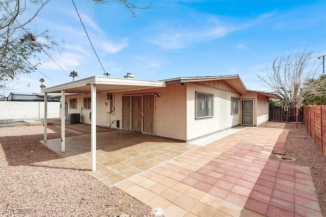 rear view of property with a patio, a carport, central AC unit, and a fenced backyard