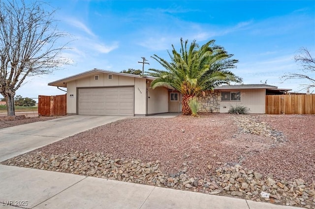 ranch-style home featuring a garage, driveway, and fence