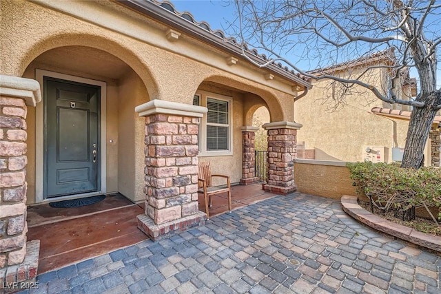 property entrance with stucco siding and stone siding