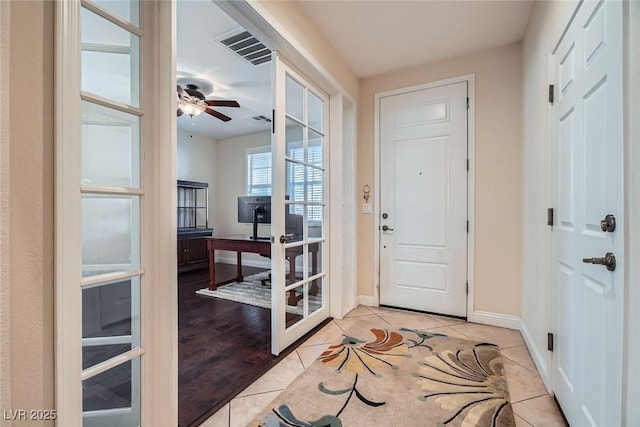 foyer featuring light tile patterned flooring, visible vents, a ceiling fan, and baseboards