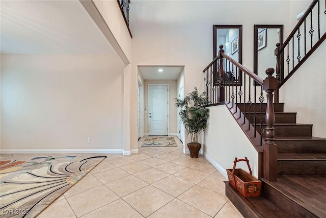 entryway featuring stairway, baseboards, a high ceiling, and light tile patterned flooring