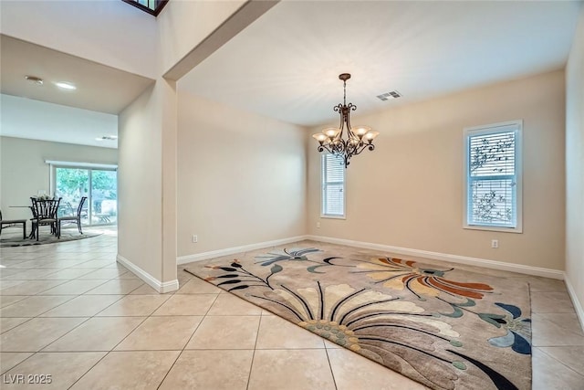 empty room with light tile patterned flooring, visible vents, a chandelier, and baseboards