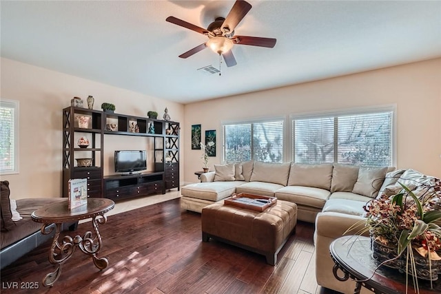 living room with a wealth of natural light, visible vents, wood-type flooring, and a ceiling fan