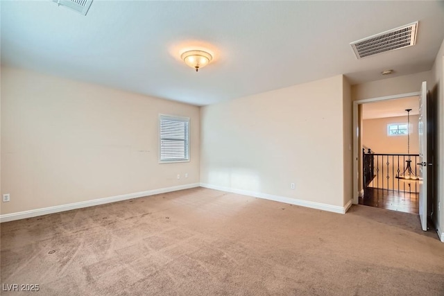 carpeted empty room featuring visible vents, baseboards, and a healthy amount of sunlight