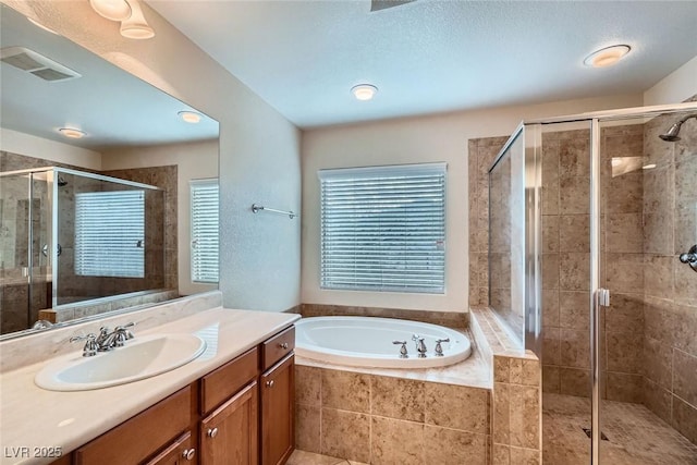 bathroom featuring vanity, a shower stall, a bath, and visible vents