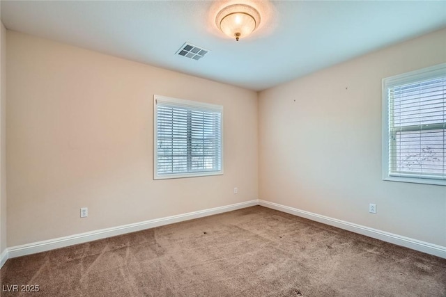 unfurnished room with a healthy amount of sunlight, visible vents, carpet floors, and baseboards