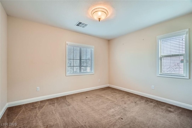 empty room with carpet flooring, baseboards, and visible vents