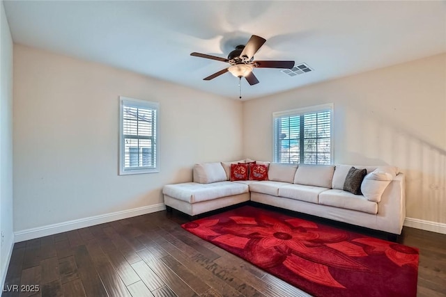 living room featuring dark wood-type flooring, visible vents, a wealth of natural light, and ceiling fan