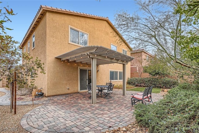 rear view of property featuring a patio, a pergola, and stucco siding