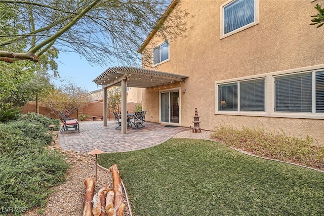 rear view of property featuring fence, a patio area, a pergola, and stucco siding