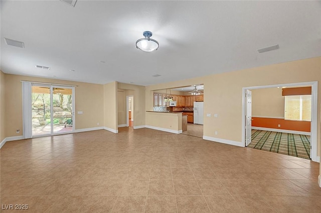 unfurnished living room featuring light tile patterned floors, visible vents, baseboards, and ceiling fan