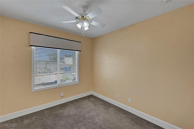 empty room with dark carpet, a ceiling fan, and baseboards