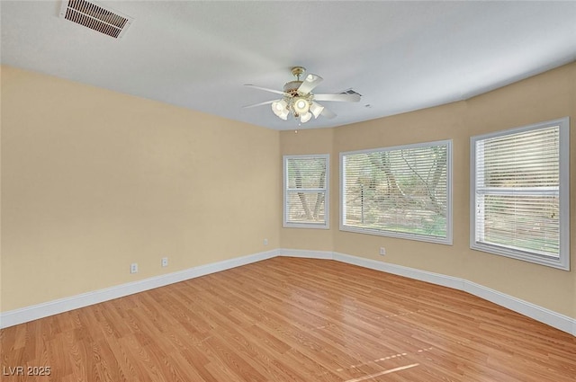 spare room featuring light wood-type flooring, visible vents, baseboards, and a ceiling fan