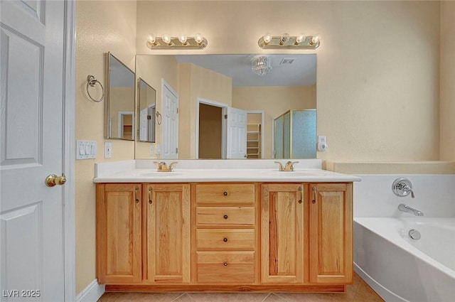 bathroom with tile patterned floors, a garden tub, double vanity, and a sink