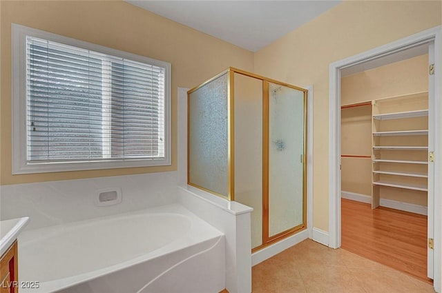 full bathroom with tile patterned floors, a shower stall, a spacious closet, a bath, and vanity