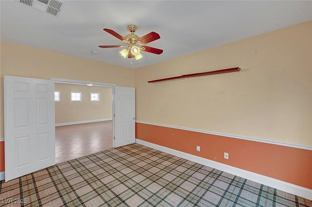 spare room featuring light tile patterned floors, visible vents, baseboards, and a ceiling fan