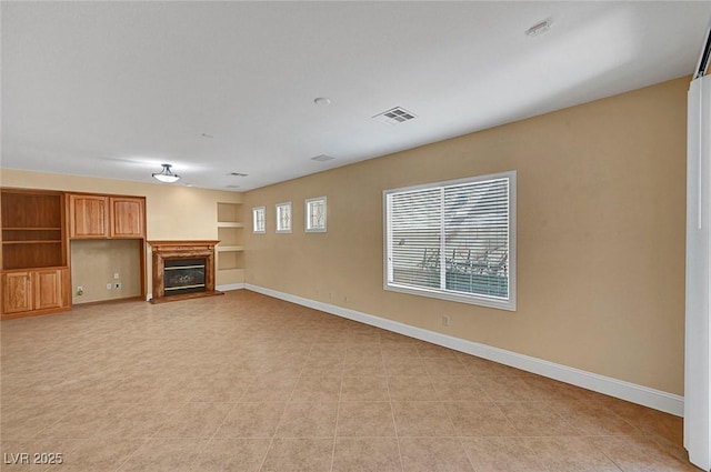 unfurnished living room with visible vents, baseboards, and a glass covered fireplace