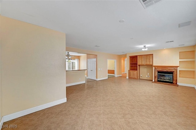 unfurnished living room with a glass covered fireplace, visible vents, and baseboards