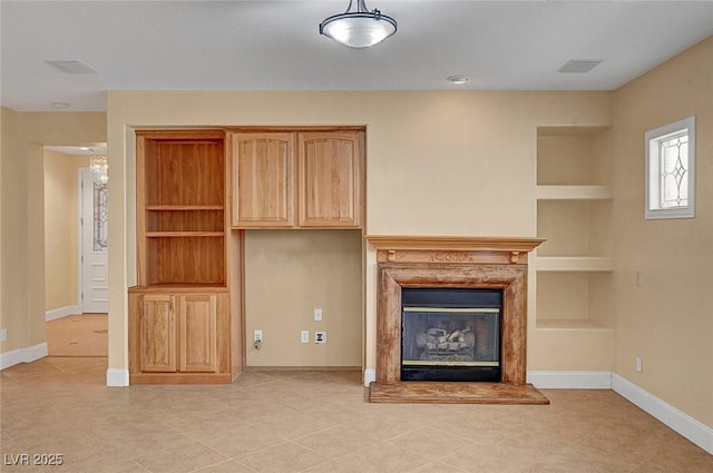 unfurnished living room with built in features, visible vents, baseboards, and a premium fireplace