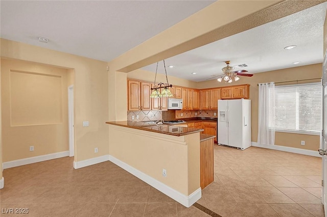 kitchen featuring tasteful backsplash, baseboards, ceiling fan, a peninsula, and white appliances