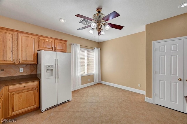 kitchen with a ceiling fan, dark countertops, white fridge with ice dispenser, light tile patterned floors, and baseboards