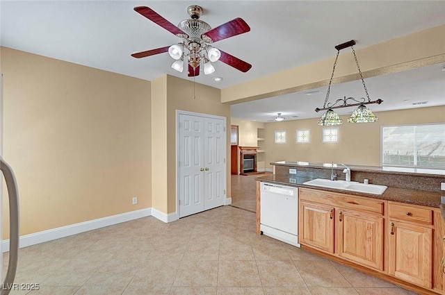 kitchen featuring light tile patterned flooring, white dishwasher, ceiling fan, a sink, and dark countertops