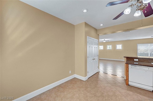 kitchen featuring dark countertops, white dishwasher, light tile patterned floors, baseboards, and ceiling fan