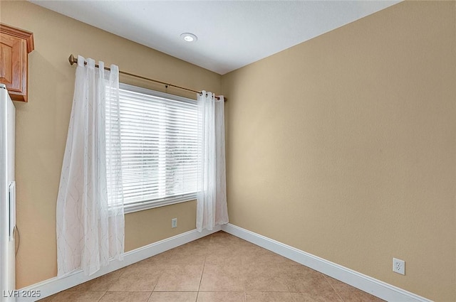 spare room featuring baseboards and light tile patterned flooring