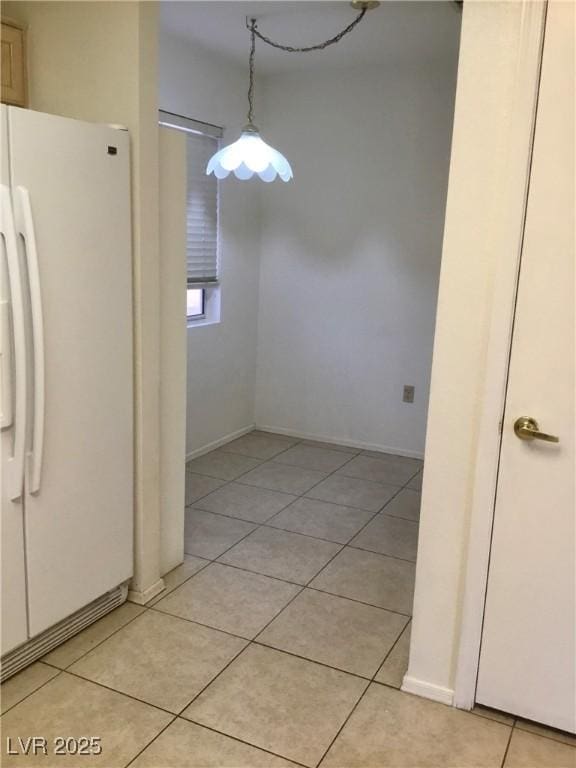 unfurnished dining area with light tile patterned floors and baseboards