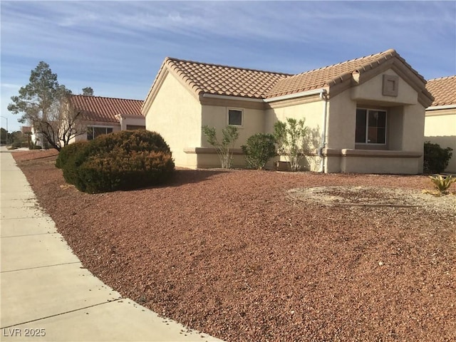 view of side of home featuring stucco siding and a tile roof