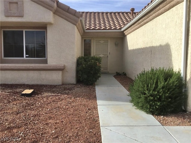 doorway to property featuring stucco siding and a tile roof