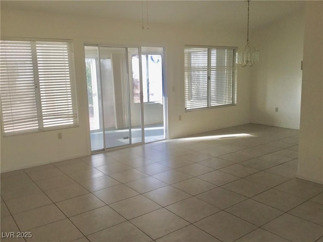 spare room with light tile patterned floors and a chandelier