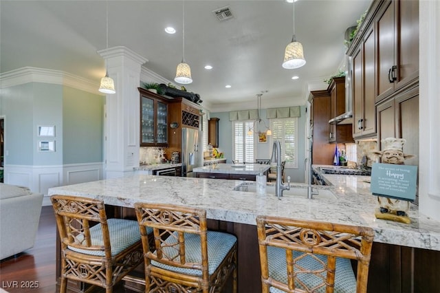 kitchen featuring a wainscoted wall, visible vents, stainless steel refrigerator with ice dispenser, crown molding, and light stone countertops