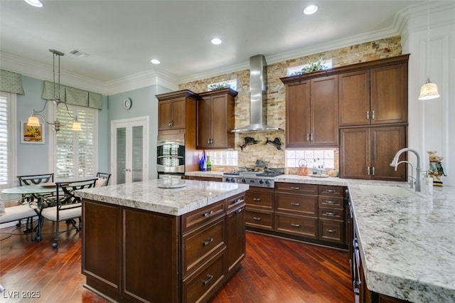 kitchen with dark wood-style floors, visible vents, a sink, appliances with stainless steel finishes, and wall chimney exhaust hood