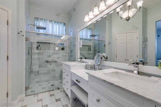 bathroom featuring a shower stall, double vanity, a chandelier, and a sink