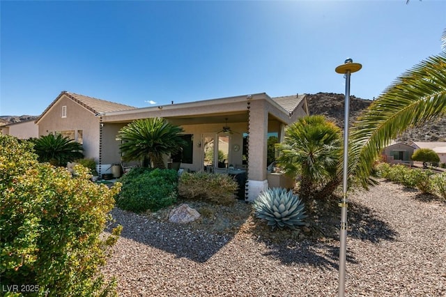 exterior space with stucco siding, a tiled roof, and ceiling fan