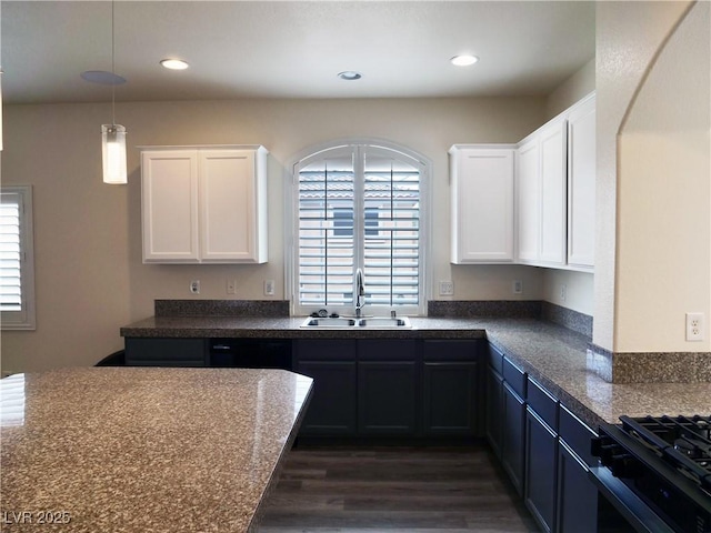 kitchen with dark countertops, dark wood-style flooring, white cabinetry, and a sink