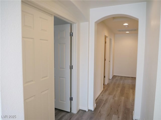 hallway featuring visible vents, wood finished floors, recessed lighting, arched walkways, and baseboards