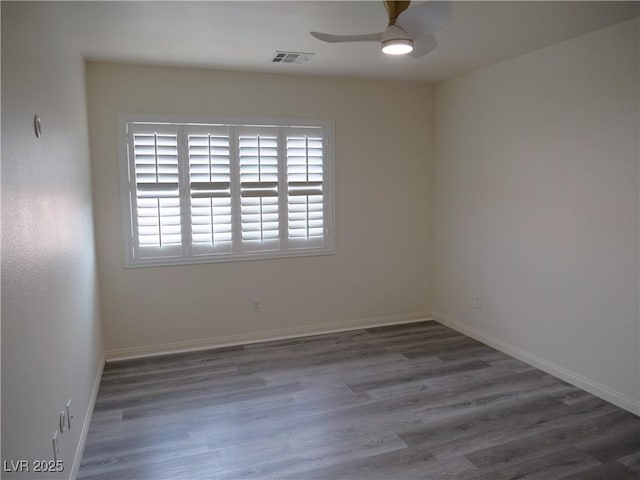 spare room featuring visible vents, baseboards, wood finished floors, and a ceiling fan