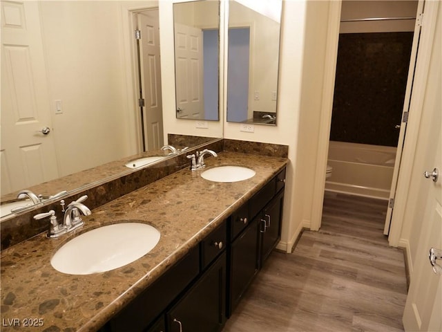 full bathroom featuring toilet, wood finished floors, and a sink