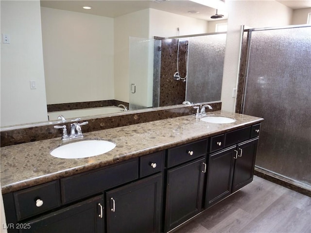 bathroom featuring a stall shower, wood finished floors, and a sink