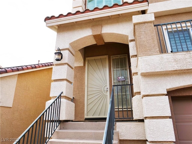 view of exterior entry featuring a tiled roof and stucco siding