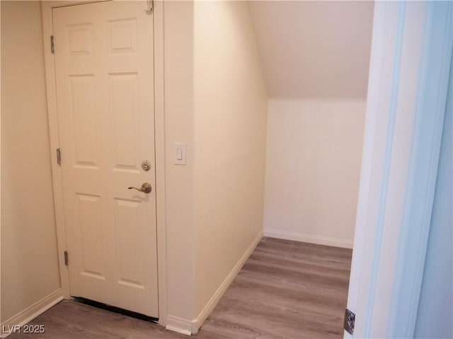 interior space featuring vaulted ceiling, wood finished floors, and baseboards