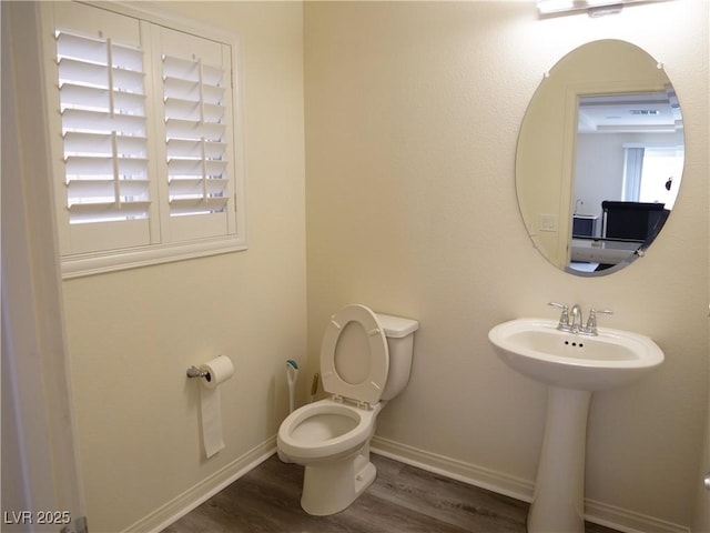 bathroom with a sink, toilet, baseboards, and wood finished floors